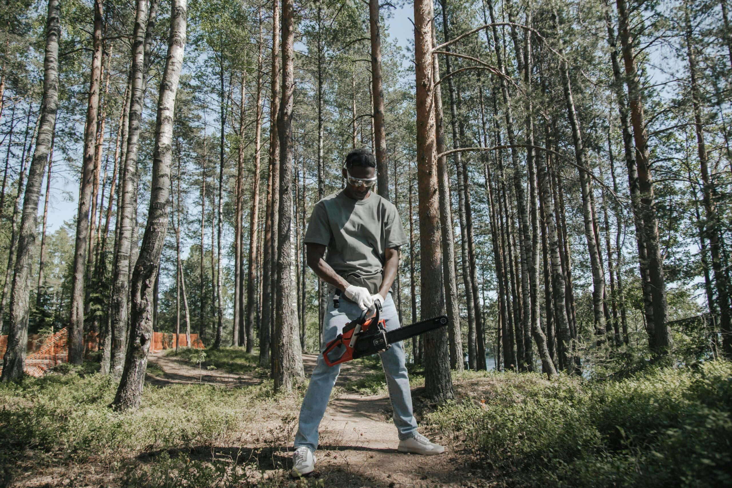 African American man operating a chainsaw in a forest setting.